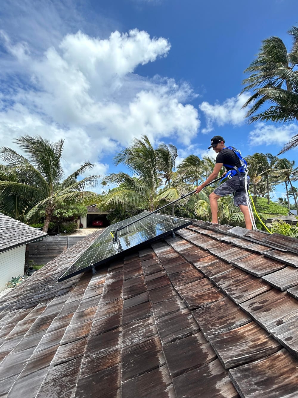 Soltra cleaning solar panels on a tile roof, harnessed for safety